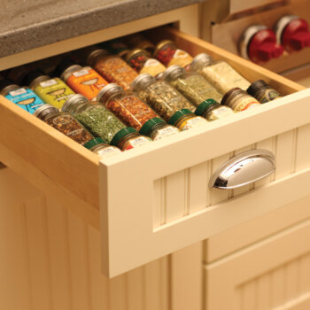A neatly organized spice rack cabinet drawer in a cottage style kitchen makes the labels easy to read.